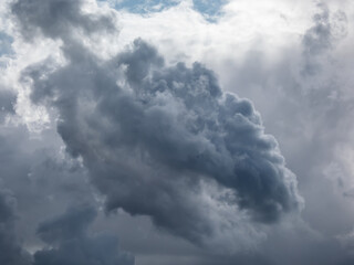 View of dark sky with fluffy white and gray clouds. Dark sky sunlit with contrasting clouds