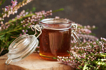 Herbal syrup in a glass jar with fresh wild heather flowers harvested in the forest