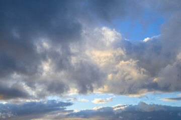 Naklejka premium Sky with white and grey storm clouds with blue sky and sun hidden behind the clouds horizontally