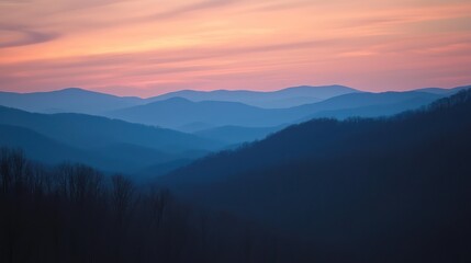 Obraz premium Sunset hues casting a serene silhouette of layered mountains.
