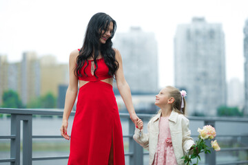 Obraz premium Mother and Daughter Enjoying a Joyful Stroll in the City on a Cloudy Day
