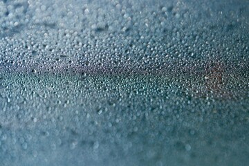 Jasne niebieskie tło. Tekstura kropli wody na płaskiej powierzchni i bokeh