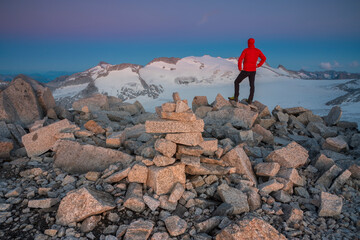 Mountaineer watches sunset frome the mountain peak, Valle Camonica, Italian Alps, Lombardy, Italy.