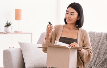 Beauty Box Concept. Portrait of smiling asian woman received delivery package, holding foundation...