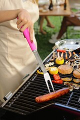 the person grills meat and vegetable skewers on an outdoor grill, using a pink basting brush to add...