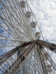 white ferris wheel of the type typically found in a funfair or seaside resort against a blue summer sky with white clouds