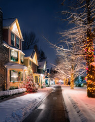 Fototapeta premium A picturesque winter street lined with houses adorned with twinkling lights and snow-covered trees, creating a magical Christmas scene