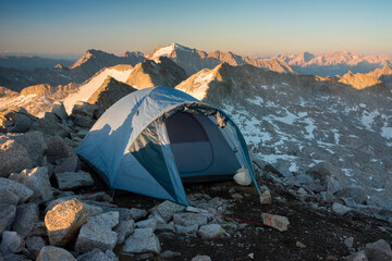 Camping tent on the mountain peak during sunset, Valle Camonica, Italian Alps, Lombardy, Italy.