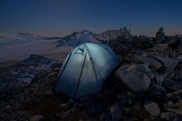 Camping tent on the mountain peak during full moon night, Valle Camonica, Italian Alps, Lombardy, Italy.