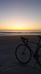 Fototapeta premium Bicycle on sandy beach at sunrise with ocean view