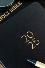 2025 calendar notebook with holy bible book. Close-up. Christian education and learning commitment,...