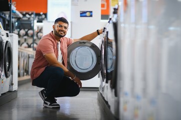 Young man buying new washing machine in store