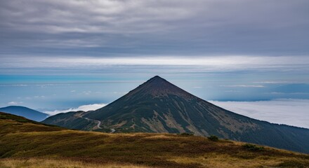 Obraz premium Majestic mountain peak rising above cloud-covered valley under dramatic sky