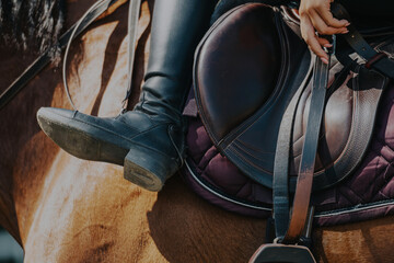A detailed shot of a rider's black boot resting in a stirrup on a well-crafted saddle, showcasing...