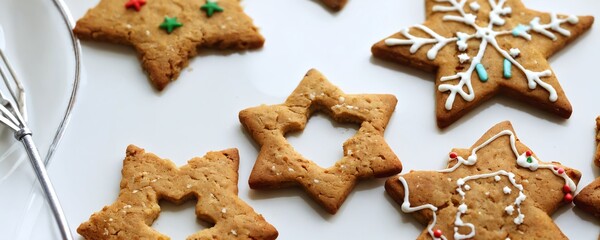 Festive holiday cookies decorated with icing and sprinkles arranged on a white plate during a celebration. Christmas and New Year