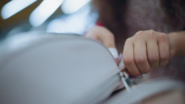 Close-up of a woman s hand as she opens a small, elegant bag, her wrist is adorned with bracelets, and the background is softly blurred, as she drops something into the bag