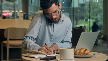 Multitasking busy serious businessman Arabian Indian male guy business man worker visitor in cafe...