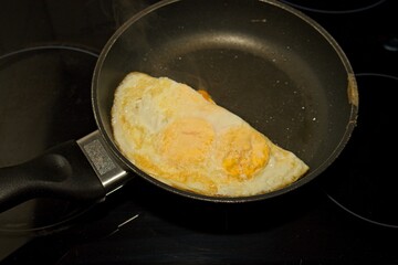 Eggs frying in a frying pan making a cheese omelet on the hob.
