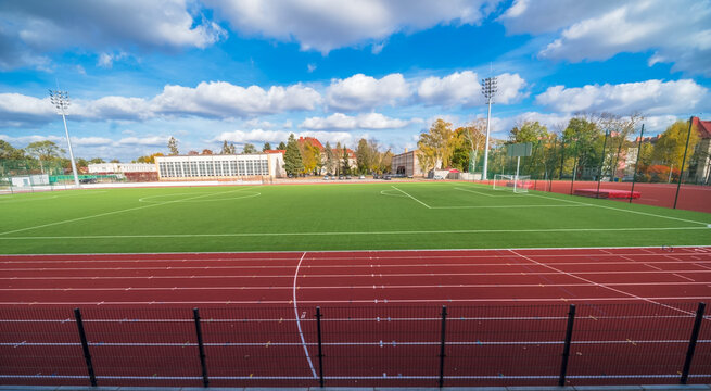 Widok na  szkolny stadion sportowy  - boisko piłkarskie  i bieżnia - z trybun dla widz&oacute;w Duże boisko otoczone bieżnią - stadion szkoły w mieście (Ostrowiec) w pięknym otoczeniu Polskiej Złotej Jesieni