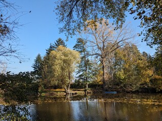 Fototapeta premium Vivid autumn panorama of a riverside pedestrian path near Pisarky in Brno, Czech Republic, with colorful foliage and calm natural surroundings.