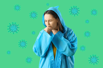 Young woman in raincoat suffering from sore throat on green background