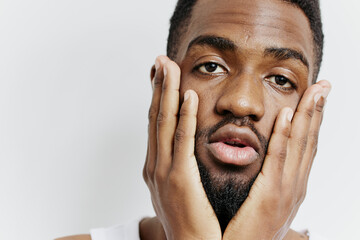 Pensive black man holding face in hands, gazing intently at camera in thoughtful expression