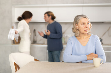 Distressed mature woman is present during quarrel between her daughter and boyfriend. Wife and...