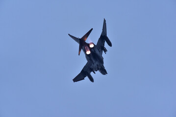 A dynamic photograph of a two engine  fighter jet soaring through the sky with its afterburners...