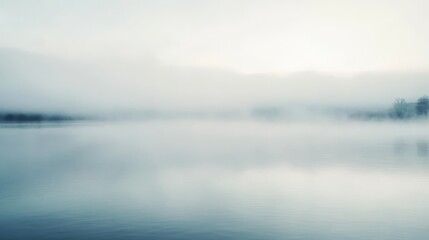 Fototapeta premium Serene misty lake at dawn, calm water reflecting soft light.