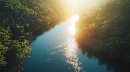 Obraz premium Serene Aerial View of Calm River Surrounded by Lush Green Forest at Sunrise with Soft Golden Light Reflecting on Water Surface