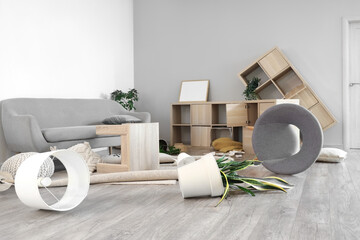 Interior of messy living room with overturned furniture after earthquake