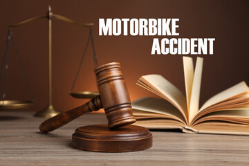 Motorbike accident law. Judge's gavel, scales of justice and book on wooden table against brown...
