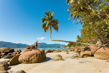 Woman on Aventureiro beach, view of this tropical paradise on Ilha Grande with famous palm, crooked...