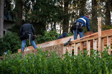 Workmen high up on a new house in the wood framing stage of building, carpenters working on a wet fall day
