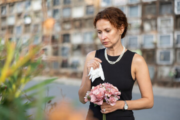 Visit to cemetery, woman in mourning clothes grieves for deceased relative. Near grave widow...