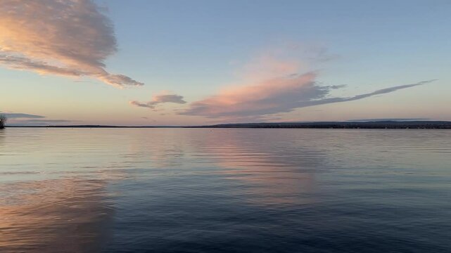 A breathtaking sunset over the Ottawa River, Canada, with soft pastel colors reflected in the calm water. The horizon and scattered clouds create a serene and tranquil atmosphere