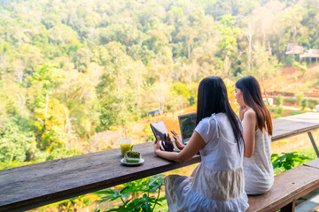 Asian businesswoman remote working online corporate business on laptop computer and digital tablet with internet at cafe. Woman freelancer enjoy outdoor lifestyle work and travel on holiday vacation.