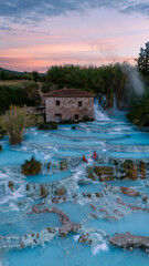 Relaxing in the natural hot springs of Saturnia, Tuscany at sunset