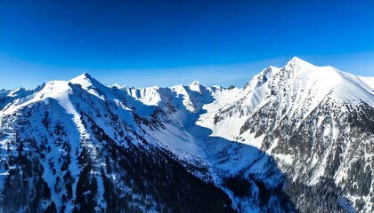 Aerial view of a snowy mountain range, with sharp peaks and deep blue shadows. generative ai