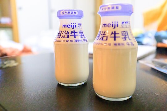 Niigata, Japan - January 5th 2024 - Photo of Refreshing Meiji Milk Bottles on a Table in Morning Light