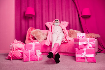 Photo of funky extravagant senior man lying fluffy sofa wear pink color boots hat in room interior...