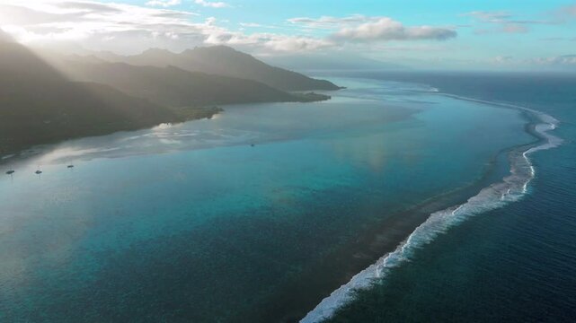 Morning sunrise boats Passe clear skies Moorea island Cooks Opunohu bay French Polynesia aerial drone lagoon coral reef waves Mount Mauaroa Tohivea Rotui Haapiti Pacific Ocean circle right motion