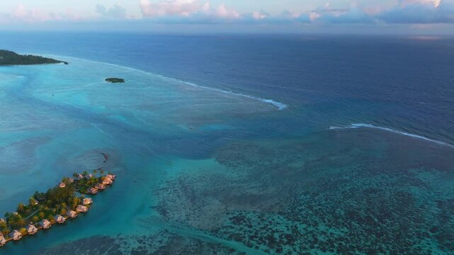 Morning islands bungalow Cooks Opunohu Bay Moorea French Polynesia aerial drone Mount Mauaroa Tohivea Rotui clouds lagoon coral reef waves vibrant green blue Pacific Ocean forward pan up motion