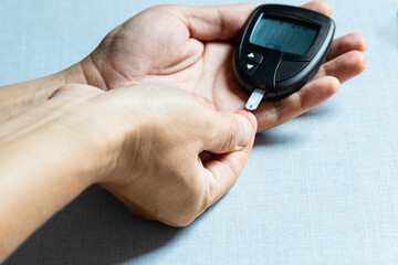 Woman's hands checking diabetes and hyperglycemia with digital blood sugar meter. Healthcare and...
