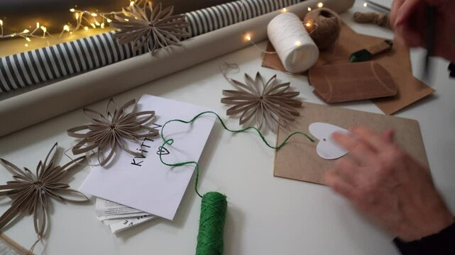 Woman writing calligraphy initials on heart shape labels for Christmas gifts