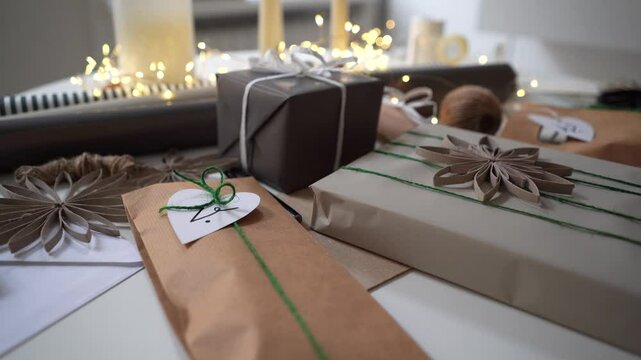 Wrapped gifts in neutral colors with string, ribbon and tags on table touched by hands