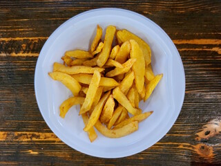 French fries in white plate on table, top view