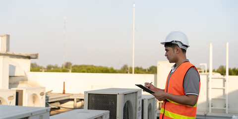 Asian maintenance engineer works on the roof of factory. contractor inspect compressor system and...