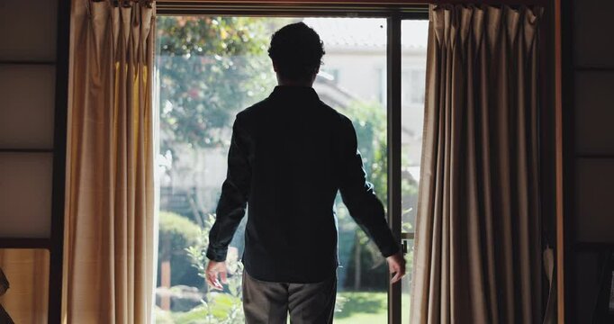 Open curtains, back and man in house, morning and start day with sunlight, calm and Japanese. Person, apartment and guy with weekend break, wake up and relax with window, comfort and accommodation