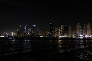 Obraz premium Beautiful night view of Dubai skyscrapers from the sea. skyline of Dubai Marina after sunset with a sea in the foreground